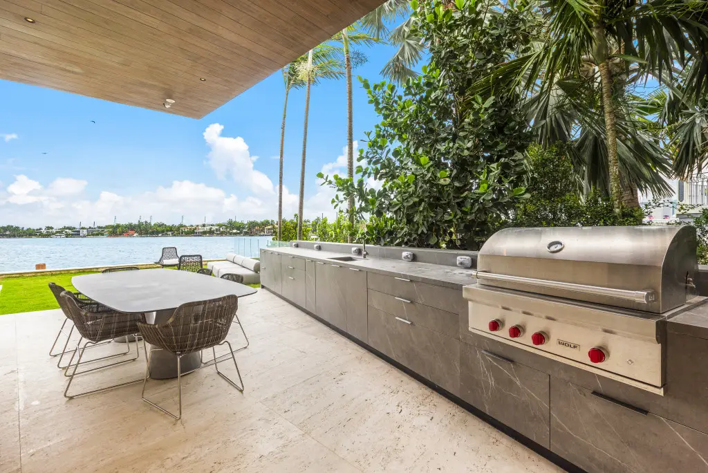 Luxury outdoor kitchen with built-in grill, dining area, and waterfront view on Venetian Island in Miami