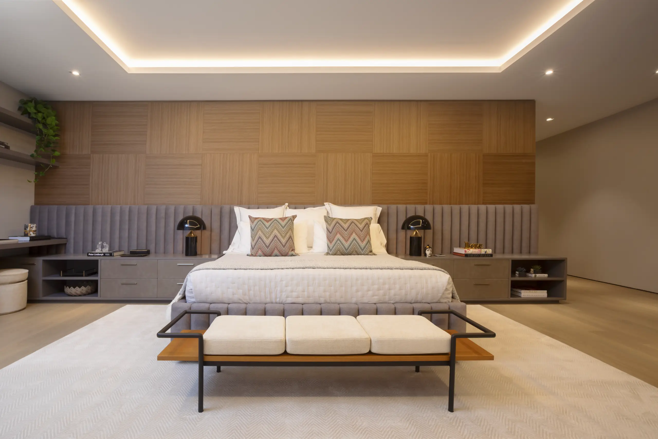 Modern primary bedroom with upholstered wall panels, wood accent wall, and custom built-in nightstands in a Venetian Island home