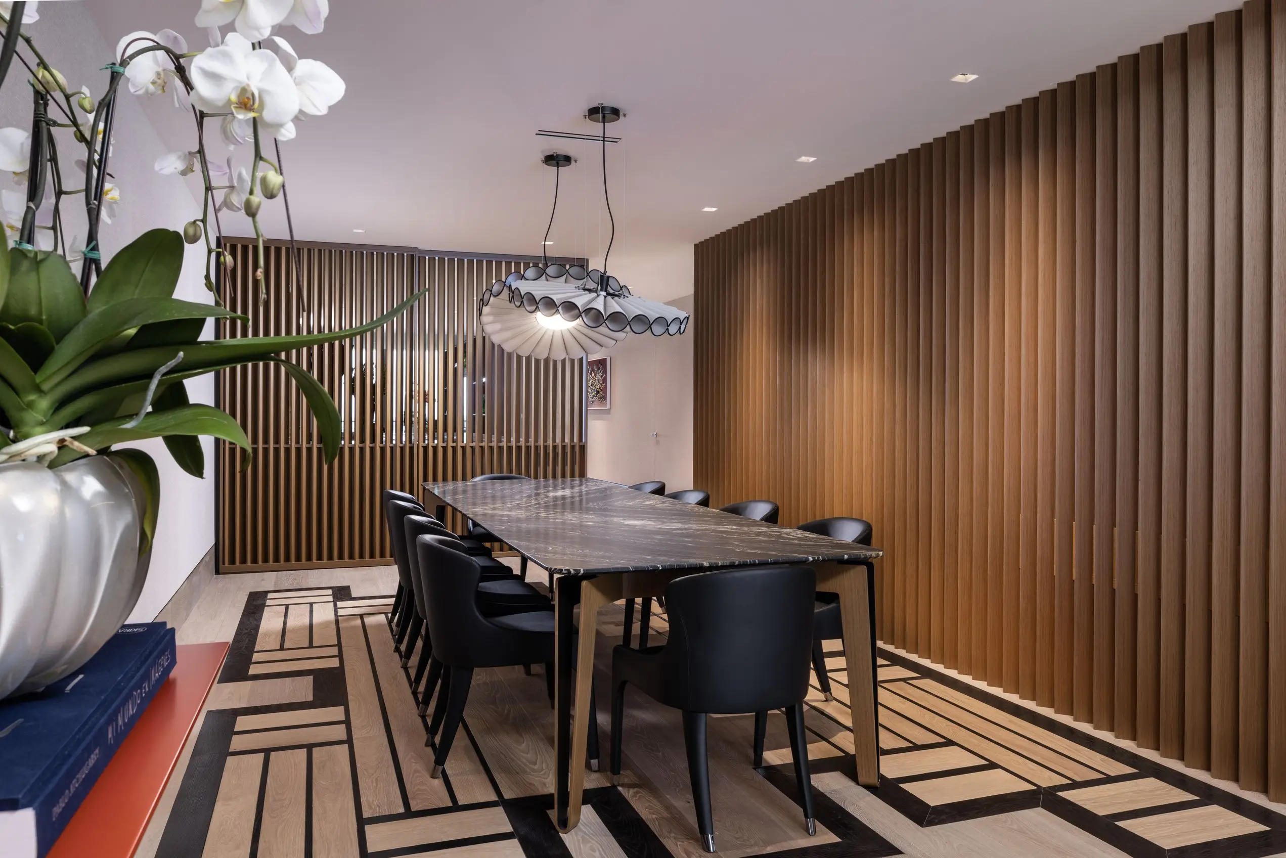Modern dining room at Oceana Bal Harbour featuring a sculptural pendant light, slatted wood accent walls, and a custom black marble table.