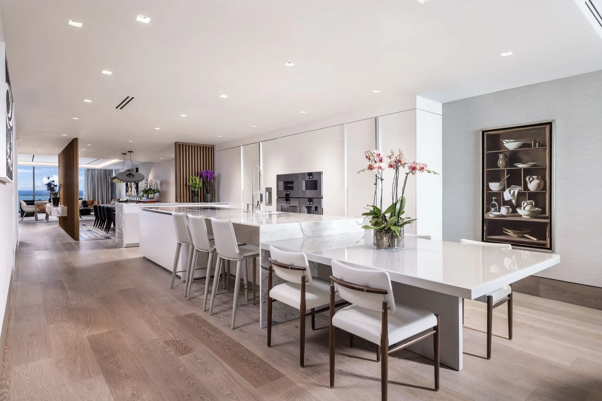 Open-concept kitchen at Oceana Bal Harbour with white marble island, integrated appliances, modern dining table, and ocean view beyond.