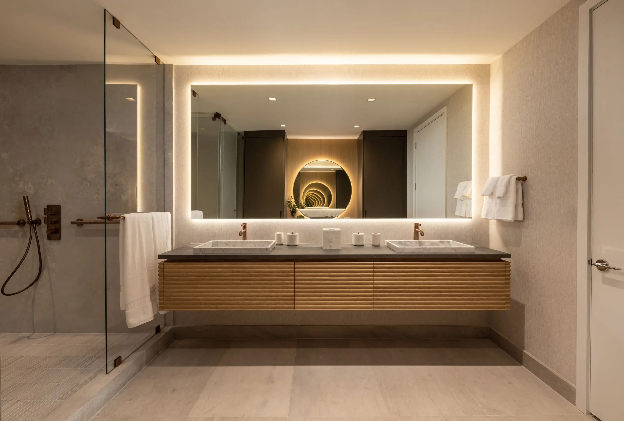 Contemporary bathroom at Oceana Bal Harbour with sculptural vanities, ambient backlit mirrors, and minimalist brass fixtures.