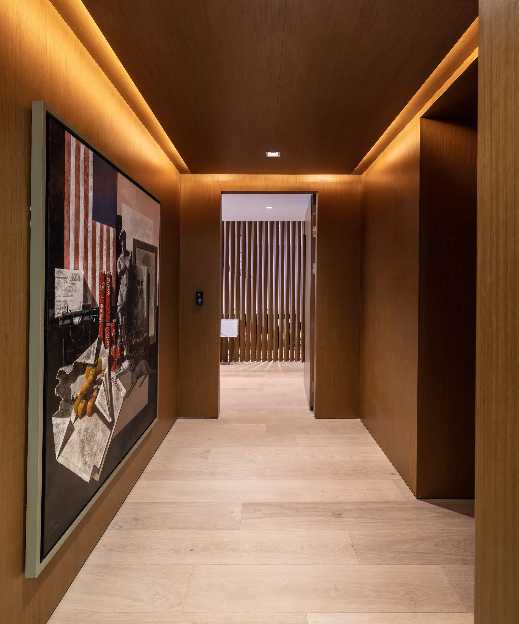 Modern hallway interior featuring warm wood paneling, recessed lighting, and a striking contemporary art piece.