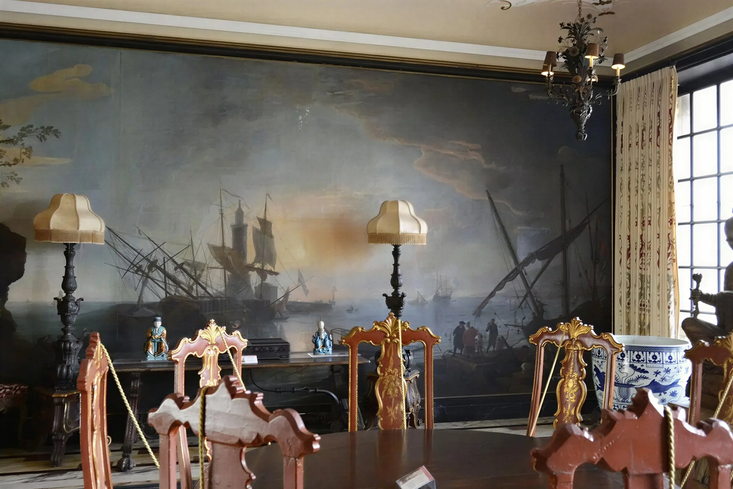 Vizcaya Museum dining room with antique carved chairs, floor lamps and large maritime mural