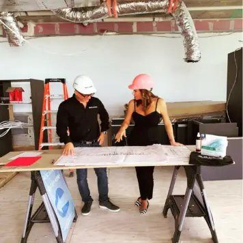 Interior designer and contractor reviewing blueprints at a construction site