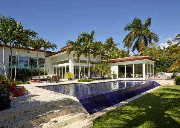 Luxury Miami home exterior with pool, palm trees and open terrace
